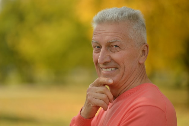 Happy elderly man enjoying in autumn park