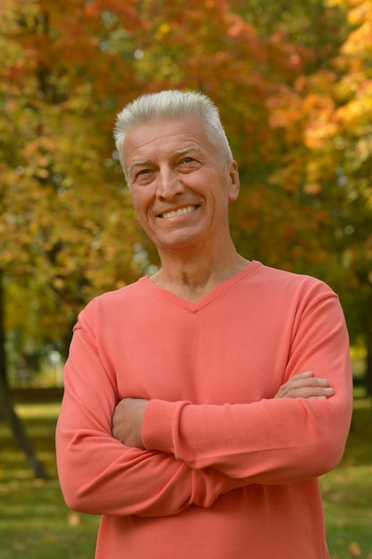 Happy elderly man enjoying in autumn park