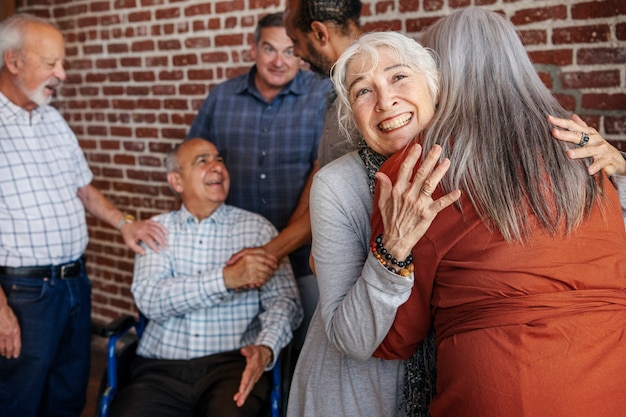 Photo happy elderly man on a wheelchair talking with friends