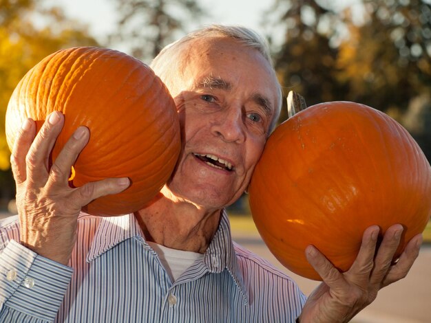 Happy elderly man with pumpkins.