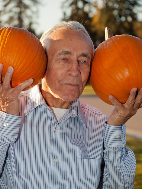 Happy elderly man with pumpkins.