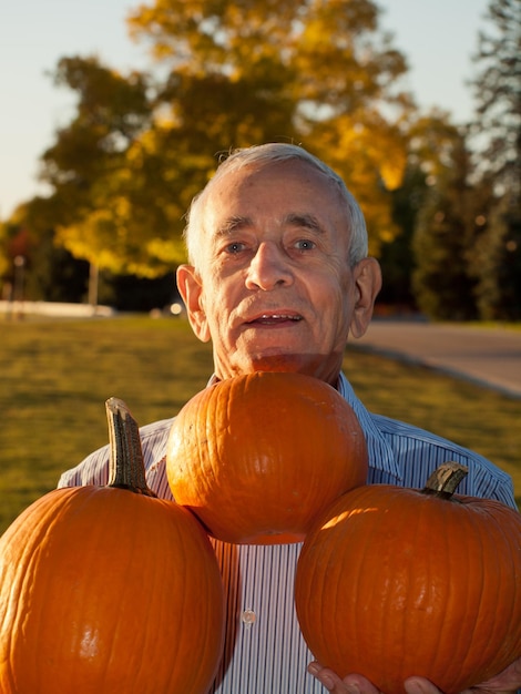 Happy elderly man with pumpkins.