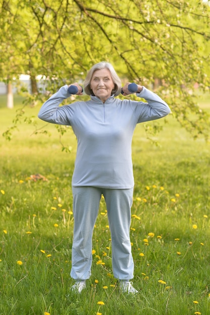 Happy elderly woman doing sports on nature in summer