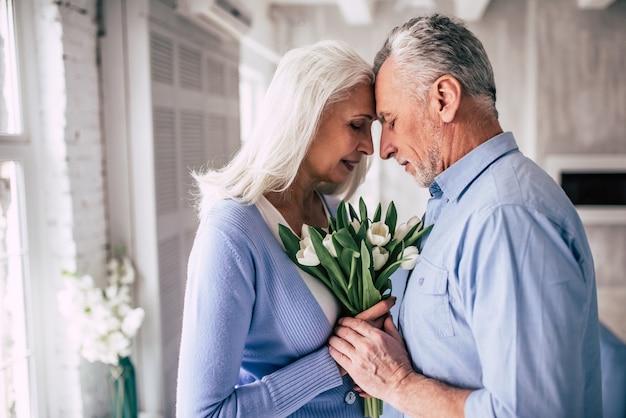 The happy elderly woman and a man standing with flowers