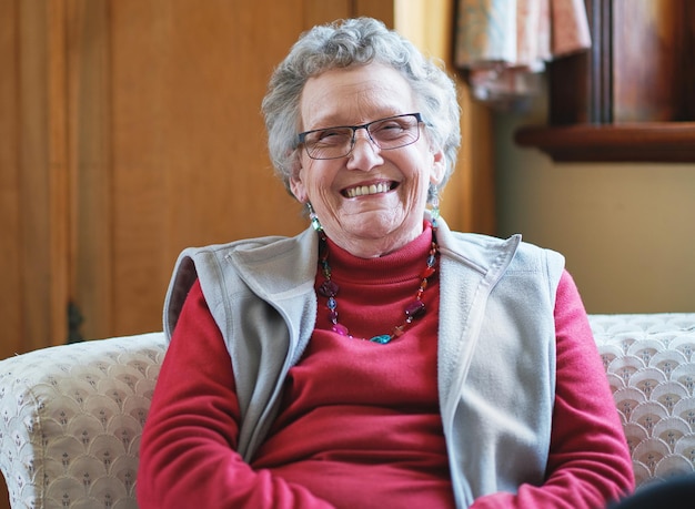 Photo happy elderly woman smiling sitting on sofa at home enjoying retirement