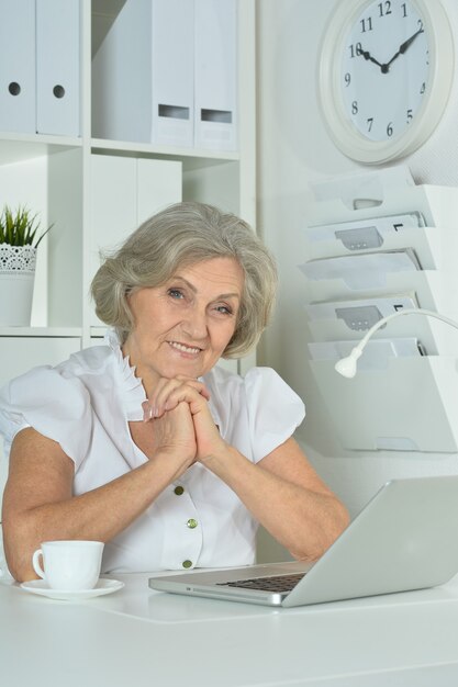 Happy Elderly woman working on laptop in office