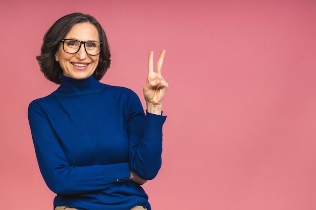 Happy elegant mature senior aged business woman smiling standing isolated over pink background. Smiling confident cheerful middle aged lady, copy space.