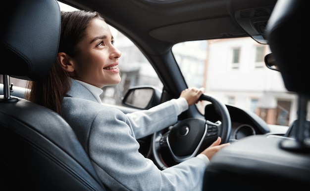 Happy elegant woman driver looking at person sitting in her car