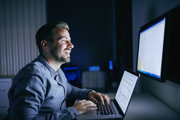 Happy employee working on the project and sitting in the office late at night.