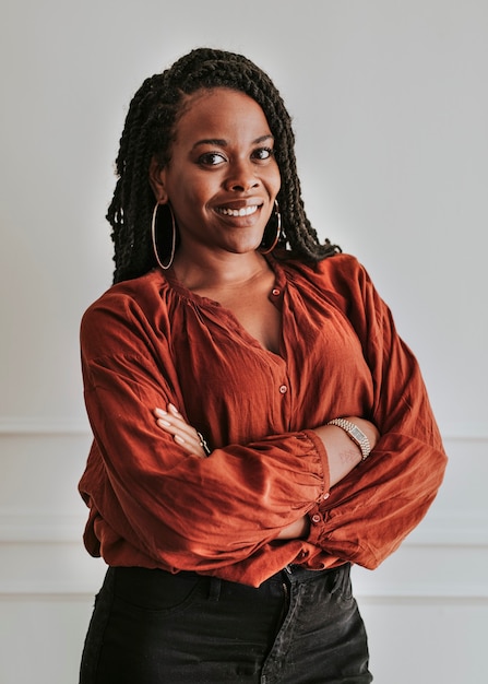 Happy empowering black woman standing by a white wall