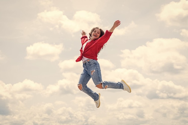 幸せなエネルギッシュな子供は自由に感じ、高い自由をジャンプします