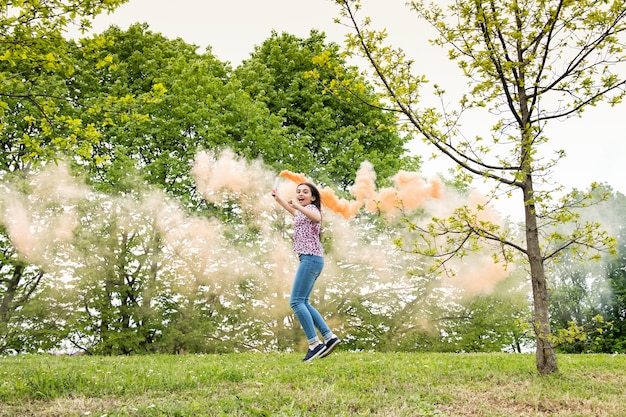 Счастливая энергичная молодая девушка с дымовой сигнальной ракеты