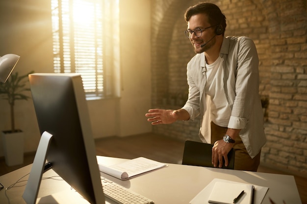 Happy entrepreneur making video call over desktop PC while working in the office