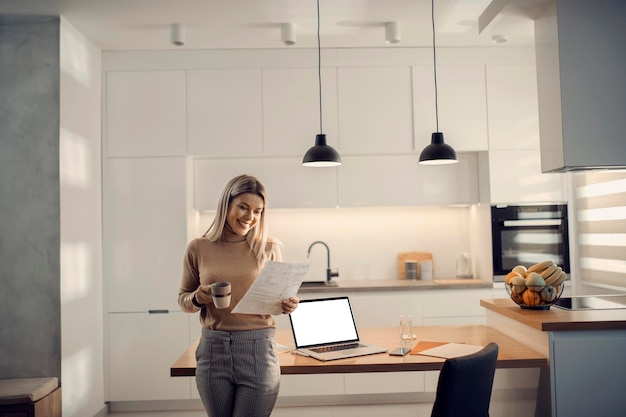 A happy entrepreneur standing in kitchen and working on paperwork