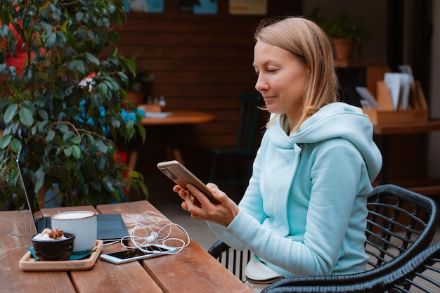 Happy entrepreneur working with a phone and laptop in a coffee shop in the street