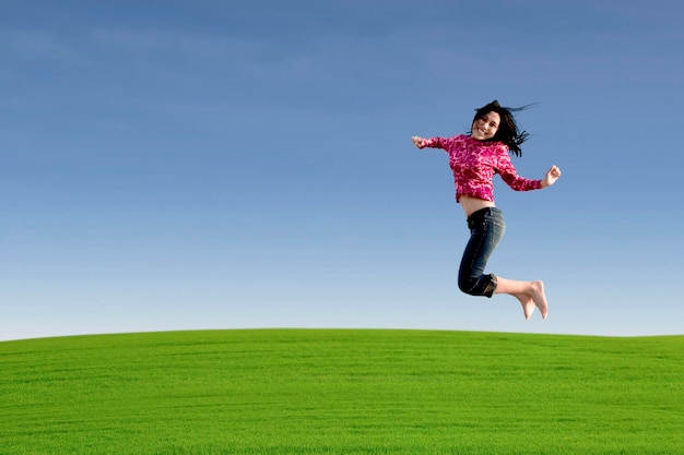 Photo happy entreprenur jumping over green field