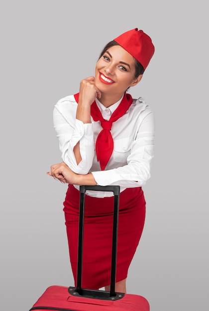 happy ethnic flight attendant leaning on luggage
