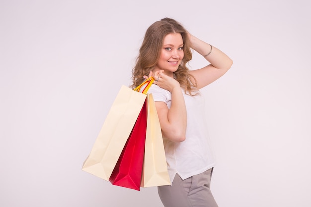 Happy european blonde woman holding shopping bags on white with copy space