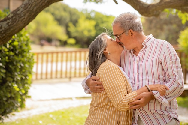 Happy european mature couple kissing enjoy date together in park at summer weekend outdoor