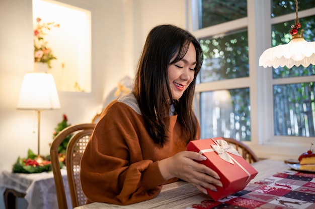写真 幸せな興奮しているアジアの女性の手がクリスマス ギフト ボックスを保持している陽気な女の子パッキング クリスマス プレゼントまたはオープン ボックス クリスマス正月誕生日ギフトxa
