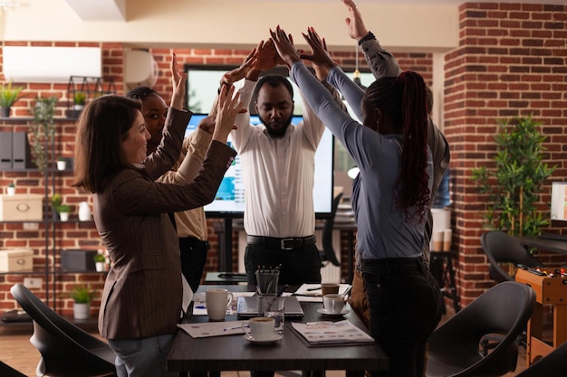 Happy excited businesspeople rising hands celebrating business collaboration winning management partnership enjoying successful deal in startup office. Diverse businessteam celebrate at workplace