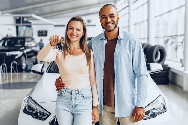 Happy excited couple or family buying a new car and showing keys