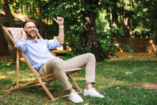 Happy excited emotional young bearded man listening music