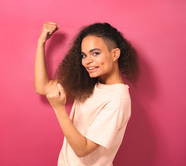 Felice ed emozionato che esprime gesto vincente giovane ragazza afroamericana che guarda positivamente la telecamera...