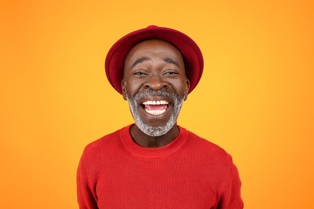 Happy excited senior african american man in hat and red clothes with open mouth