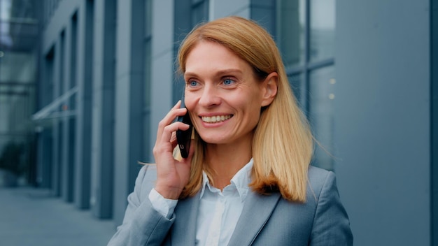 Happy excited woman talking on cellphone outdoors sharing good experience communicating with client