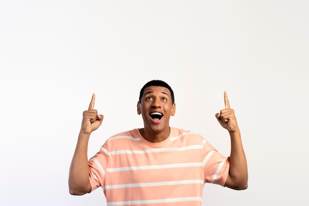 Happy excited young man looking away pointing up with fingers hand gesture at copy space