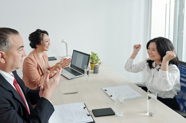 Happy excited young woman celebrating getting dream job after interview with hr manager and head of department