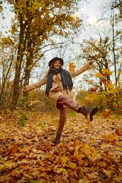 Happy excited young woman under leaves fall