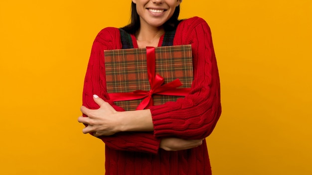 Happy excited young woman in santa claus hat with gift box over yellow background - image