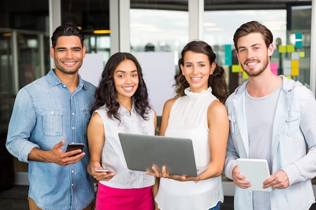 Happy executives holding laptop, digital tablet and mobile phone