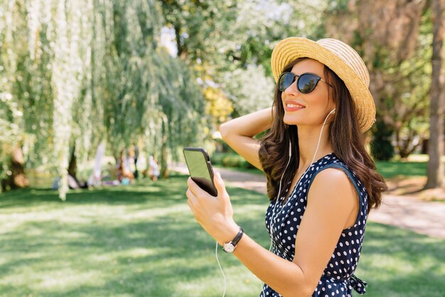 Happy exited woman listening music and enjoying summer in the park