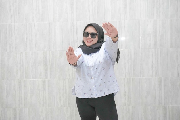 The happy expression of an Asian Indonesian hijab woman wearing a white patterned shirt