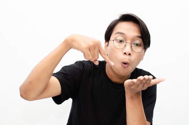 happy expressive asian young man with glasses shocked happily pointing finger and offering something