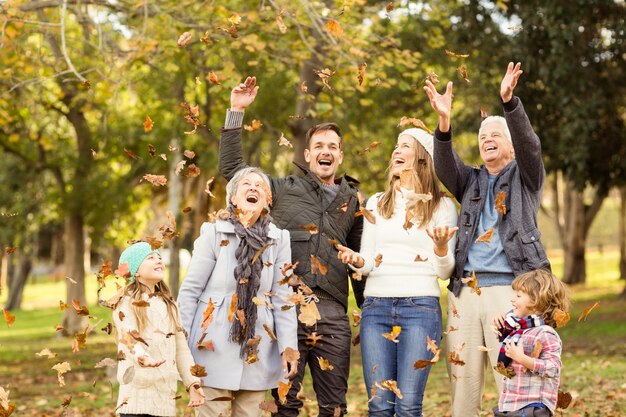 Happy extended family throwing leaves around