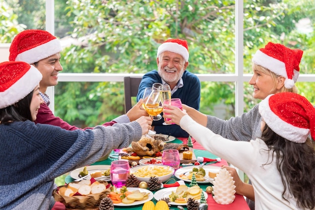 写真 一緒にクリスマス休暇を祝うために一緒に夕食をとる幸せな拡張多世代家族は眼鏡に焦点を当てます