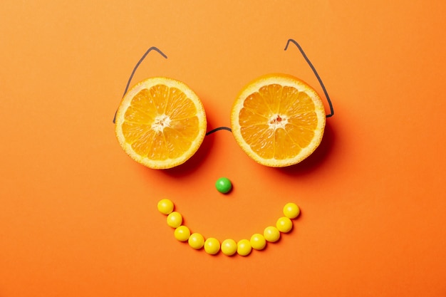 Happy face made of candies and oranges on orange