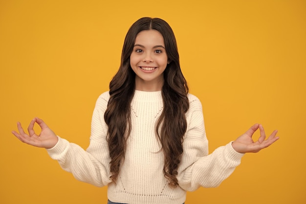 Happy face positive and smiling emotions teenager child in white shirt hold hands in yoga om aum gesture relax meditate try calm isolated on yellow background