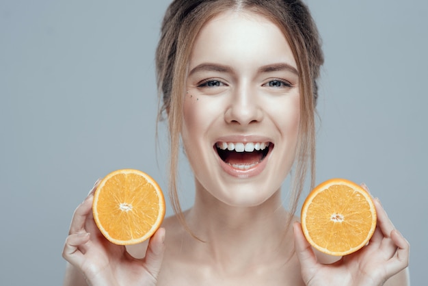 Happy face with juicy orange on grey background.