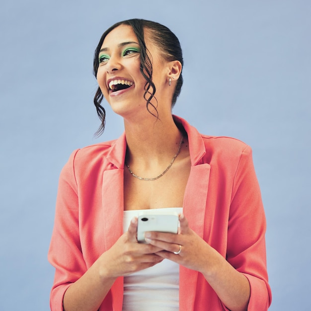 Happy face and woman with phone in studio laughing at social media joke or meme on blue background Smartphone app and female model with gif communication joke or funny chat text or blog comic