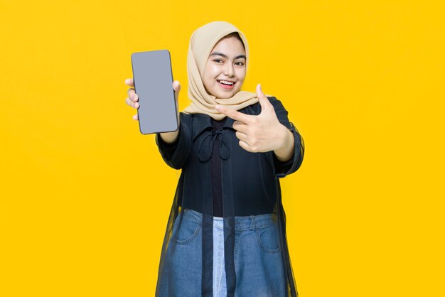 Happy face of young Asian woman with smartphone on yellow wall