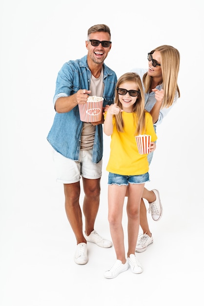 흰색으로 격리된 영화관에서 영화를 보면서 팝콘 양동이를 들고 3D 안경을 쓴 행복한 가족