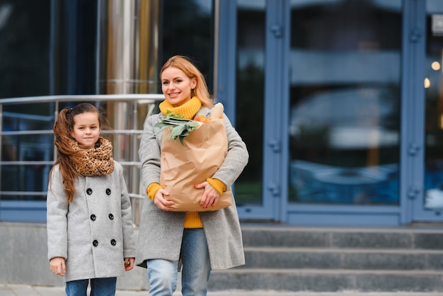 Happy family after shopping with shopping bags on parking near mall. mother with daughter.