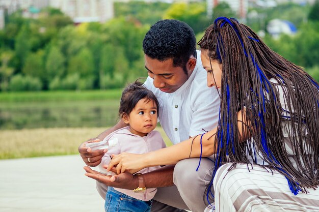 Happy family applying handsanitizer antibacterial gel to daughter hands