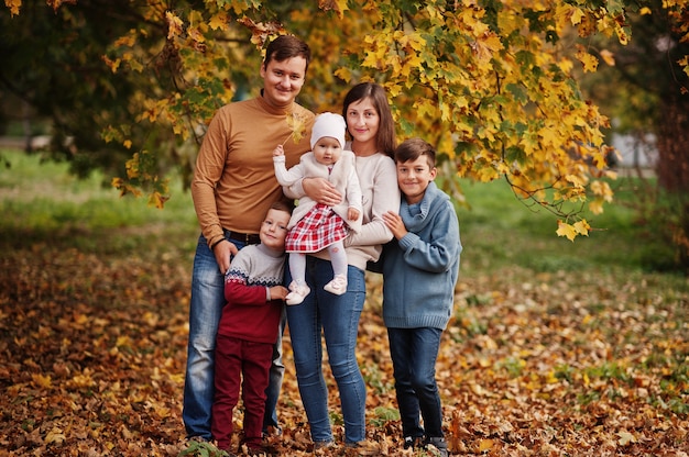 Happy family at autumn leaves park. Three kids.