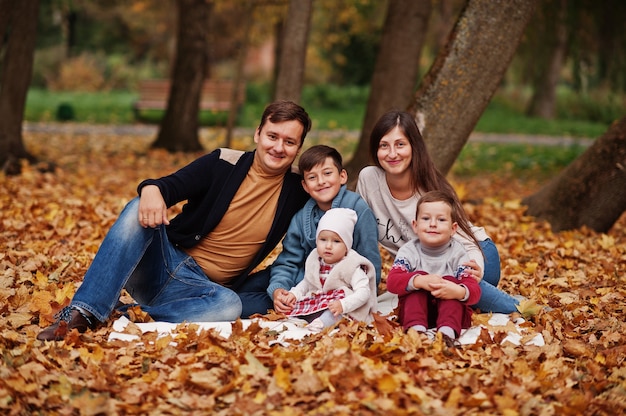 Famiglia felice al parco delle foglie d'autunno. tre bambini.